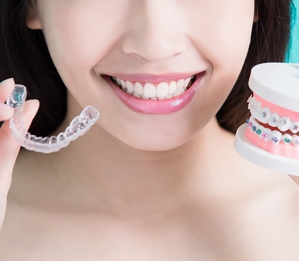 patient holding clear aligners like Invisalign® in Durham, NC